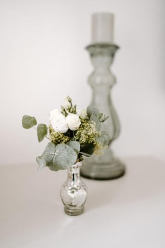 a glass vase with flowers in it next to a candle at Hotel Da Felice in Bopfingen