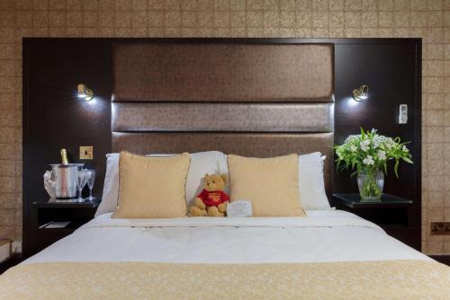 a teddy bear sitting on top of a bed at Rogerthorpe Manor Hotel in Pontefract