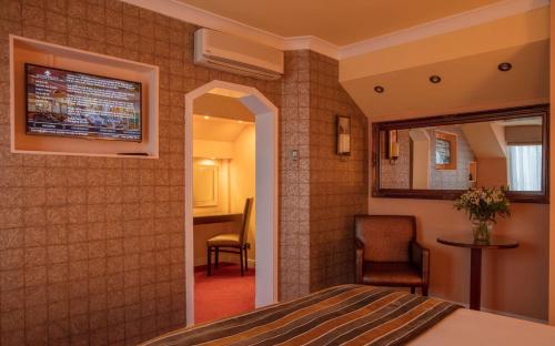 a room with a bed and a chair and a mirror at Rogerthorpe Manor Hotel in Pontefract