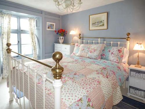 1 Schlafzimmer mit einem weißen Bett und einer floralen Tagesdecke in der Unterkunft Blue Harbour Cottage in Torquay