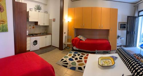 Il comprend un salon avec un lit rouge et une cuisine. dans l'établissement Appartamento affitti brevi Verona Colors/G.B. Rossi friendly, à Vérone