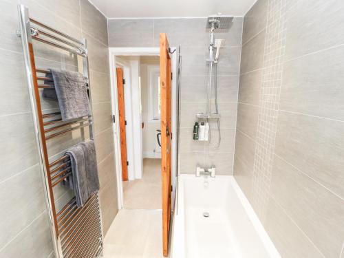 a bathroom with a bath tub and a shower at Cottongrass Cottage in Littleborough