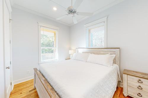 a white bedroom with a bed and two windows at Cajun Retreat in Dauphin Island