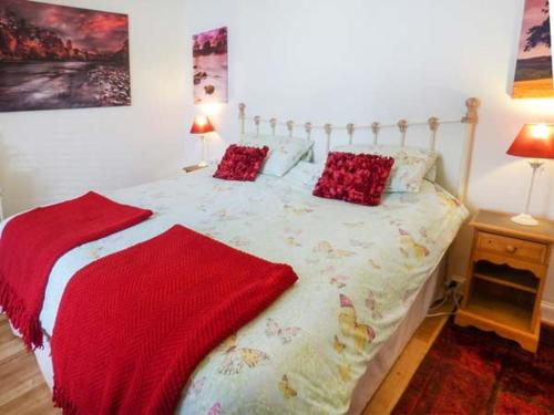 a bedroom with a bed with red pillows on it at 3 Queen Marys Buildings in Jedburgh