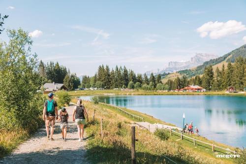 a group of people walking along a path by a lake at Au Petit Flocon - Appartement 3 pièces, central et proche pistes - parking privé et wifi in Megève