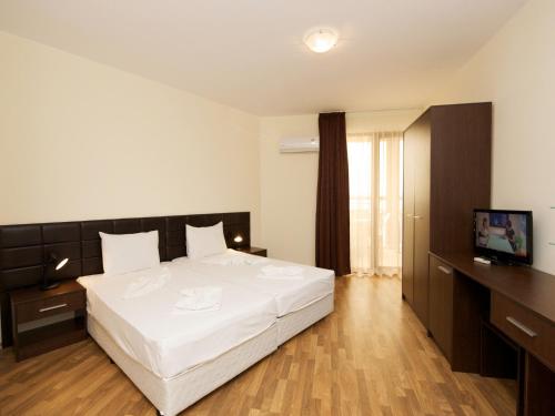 a bedroom with a large white bed and a television at Hotel Golden Ina - All Inclusive - Beachfront in Sunny Beach