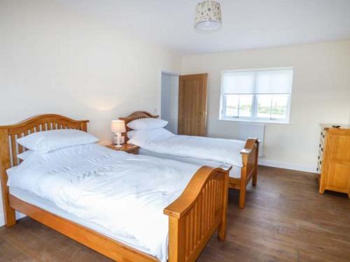 a bedroom with two beds and a window at Ysgubor Newydd in Cemaes Bay