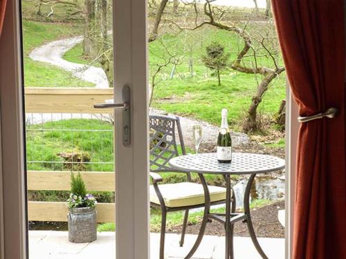 a glass door with a table and a bottle of wine at Park Brook Retreat in Scorton