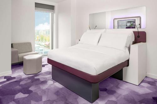 a room with a bed, a chair, and a rug at YOTEL Amsterdam in Amsterdam