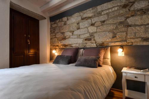 een slaapkamer met een groot bed en een stenen muur bij Cà Rosa in Mergozzo