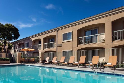 a swimming pool in front of a building with chairs at Sonesta Select Camarillo in Camarillo