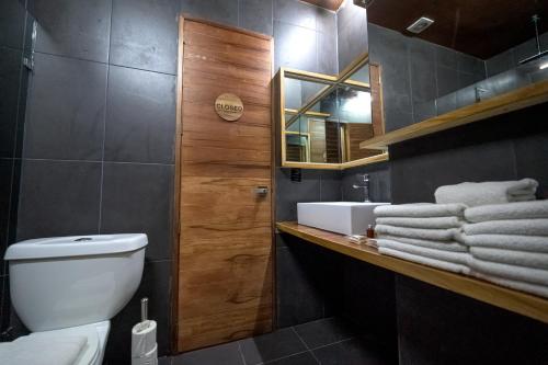 a bathroom with a toilet and a sink and towels at Reina Roja Hostal in Playa del Carmen