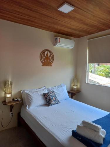 a bedroom with a bed with white sheets and a window at Maré Zen Gamboa in Morro de São Paulo