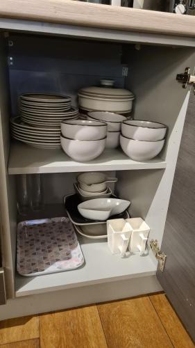 a cabinet filled with plates and bowls and dishes at Cosy 2 bedroom Apt with Fast Wi-Fi & Free Parking in Manchester