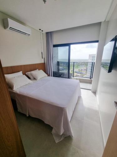 a bedroom with a white bed and a large window at SALINAS PREMIUM RESORT in Salinópolis