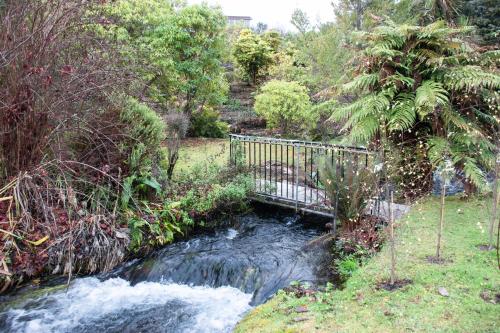a bridge over a stream in a garden at Brookside Central Wanaka Luxury Apartment in Wanaka