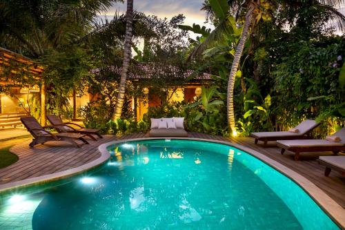 a swimming pool in a yard with chairs and trees at Casa Das Águas Trancoso in Trancoso
