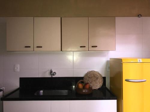 a kitchen with a sink and a bowl of fruit on a counter at Pequeno Grande Paraíso in Arraial do Cabo