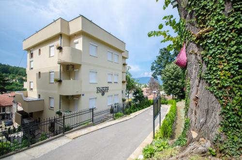 a building on the side of a road next to a tree at Apartments Biser in Vrnjačka Banja