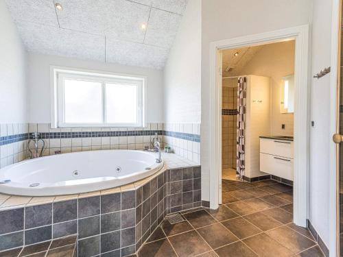 La grande salle de bains est pourvue d'une baignoire et d'une fenêtre. dans l'établissement Holiday home Blåvand CLX, à Blåvand