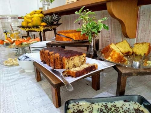 un tavolo pieno di diversi tipi di torte e pane di Pousada do Grilo a Santo Antônio do Pinhal