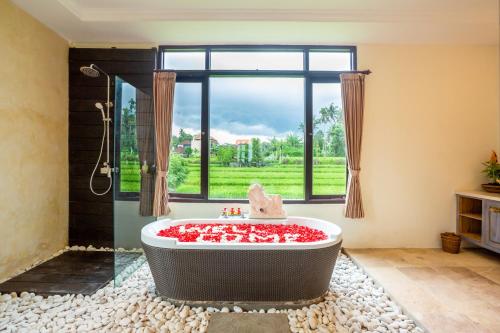 a bathroom with a bath tub with a window at Champaca Luxury Villas Ubud in Ubud