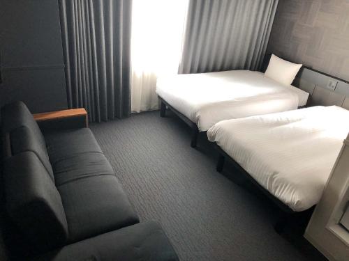 a hotel room with two beds and a couch at CHISUN STANDARD Osaka Shin-Imamiya in Osaka