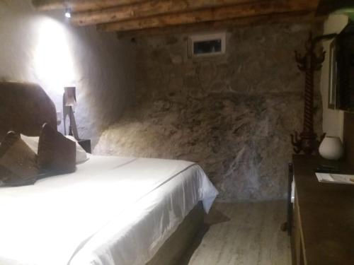 a bedroom with a bed and a stone wall at Hotel de Piedra in Bernal