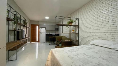 a bedroom with a white brick wall and a bed at Loft amplo, apenas 6km do Morro do Careca! (G) in Natal