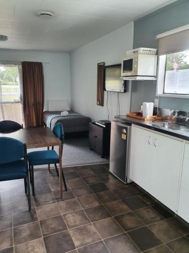 a kitchen with a table and a room with a bed at Ohakune Court Motel in Ohakune