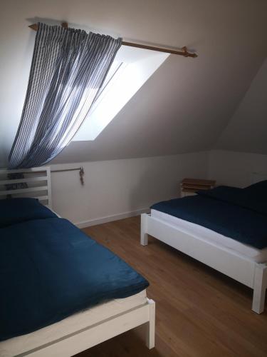 a attic bedroom with two beds and a window at Podlaski Bon Turystyczny eMKa Noclegi apartamenty in Augustów