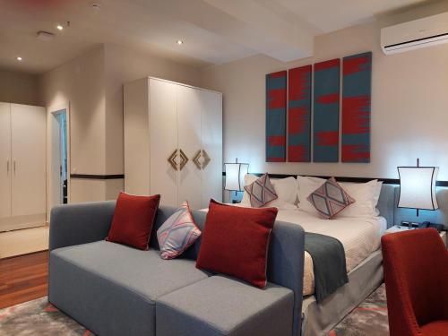 a bedroom with a bed with a couch and a painting at Somerset City Centre Atyrau in Atyraū