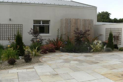 a garden with a stone patio in front of a house at Inny River Lodge in Rathowen