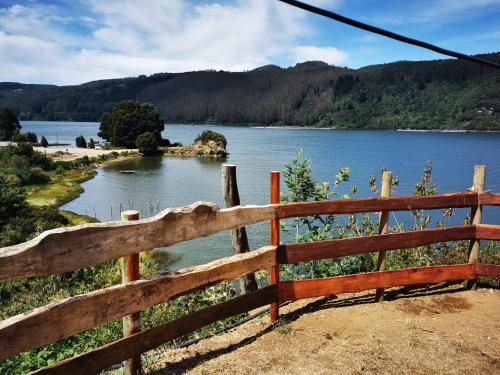 a wooden fence with a view of a lake at Camping & Cabaña Los Arrayanes Niebla in Valdivia