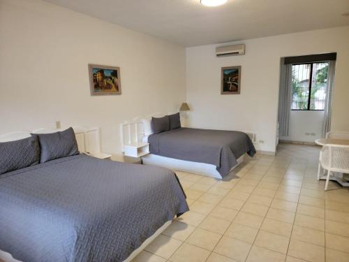 a bedroom with two beds and a table and a window at Hotel Paraiso Las Palmas in Ensenada