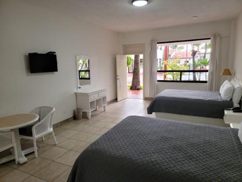 a bedroom with two beds and a table and a television at Hotel Paraiso Las Palmas in Ensenada