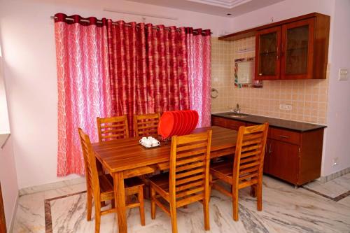 eine Küche mit einem hölzernen Esstisch und Stühlen in der Unterkunft Blue stone homestay guesthouse in Visakhapatnam