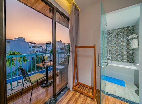 baño con bañera y balcón con vistas. en Cani Beach House, en Da Nang