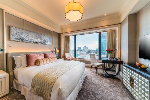 a bedroom with a large bed and a large window at Caravelle Saigon in Ho Chi Minh City
