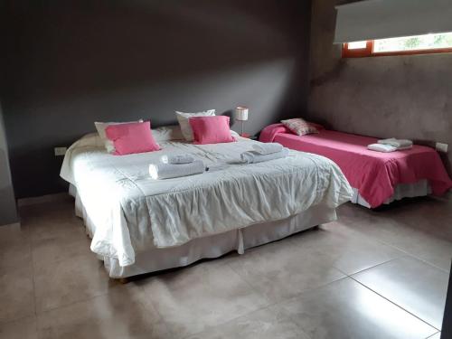 1 Schlafzimmer mit 2 Betten und rosa Kissen in der Unterkunft Hermosa casa con pileta asador patio de fuego in San Salvador de Jujuy