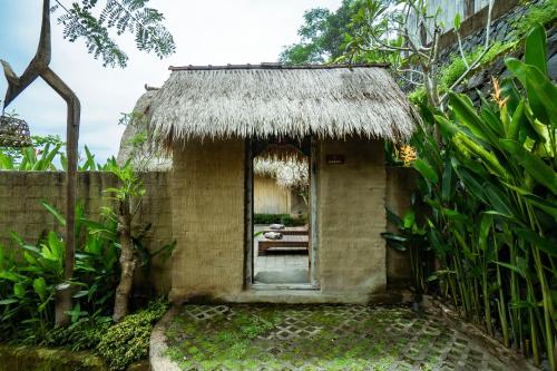 an outside view of a small house with a thatched roof at Magatama Villa by Mahaputra in Gianyar
