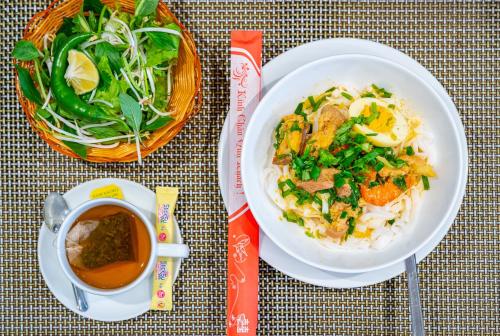 een tafel met een bord eten en een kopje koffie bij Cani Beach House in Da Nang