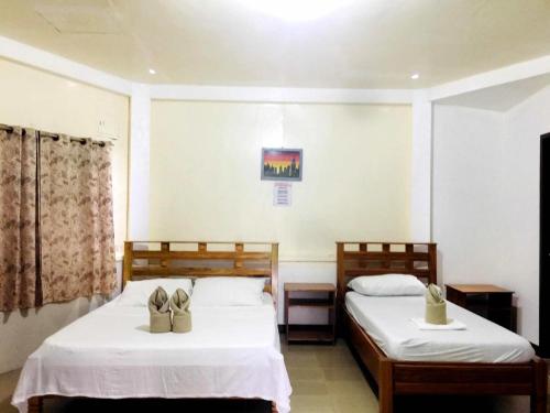 ein Schlafzimmer mit zwei Betten mit Schuhen drauf in der Unterkunft Gazebo Pools and Restaurant in Cabadbaran
