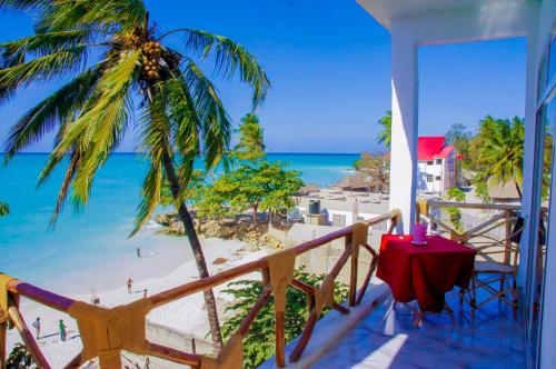 a balcony with a table and a view of the beach at Room Ally at the beach for 2 - 3 guests in Nungwi