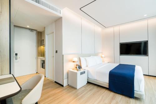 a hotel room with a bed and a table and a chair at Arbour Hotel and Residence in Pattaya Central