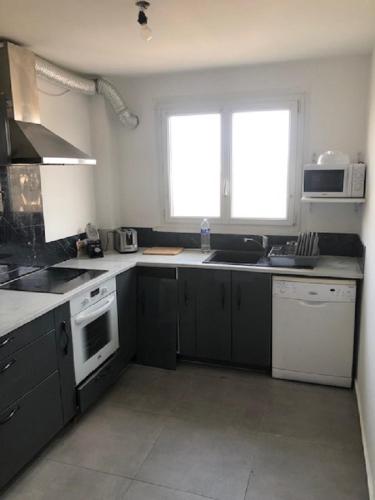 une cuisine avec des appareils en noir et blanc et une fenêtre dans l'établissement Kennedy, à Saint-Jean-de-Braye