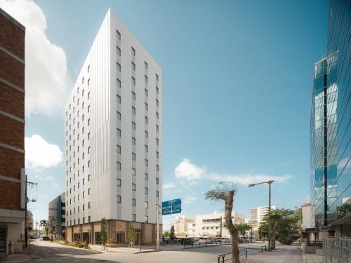 un edificio blanco alto en una calle de la ciudad en Nest Hotel Naha Nishi en Naha