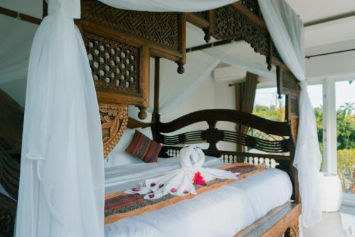 a bedroom with a canopy bed with white sheets at Villa Bukit Sing Sing in Singaraja