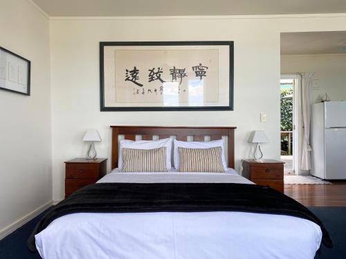 a bedroom with a large white bed with two night stands at Mangonui Waterfront Apartments in Mangonui