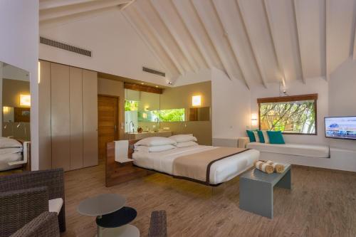 een slaapkamer met een kingsize bed en een televisie bij Cocoon Maldives - All Inclusive in Lhaviyani Atol